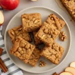 Apple Brownies (Easy Fall Dessert) 5 A round plate holds chewy Apple Brownies, an easy fall dessert with walnut tops and cinnamon sticks nearby, showcasing Fresh Apples for a classic Fall Desserts Easy bake.