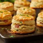 Breakfast Protein Biscuits 5 A dark sheet pan holds golden Breakfast Protein Biscuits with melty cheese and herbs, perfect for a High Protein Breakfast and quick Protein Breakfast on a Busy Morning.