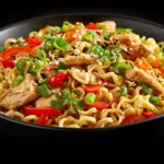 A black bowl filled with Chicken Ramen Stir Fry shows springy ramen noodles, sliced chicken, red bell peppers, scallions, cilantro, and sesame seeds in a glossy sauce, an inviting take on Chinese Cooking Recipes for Easy Chinese Recipes and Asian Dinners that fits Health Dinner Recipes.