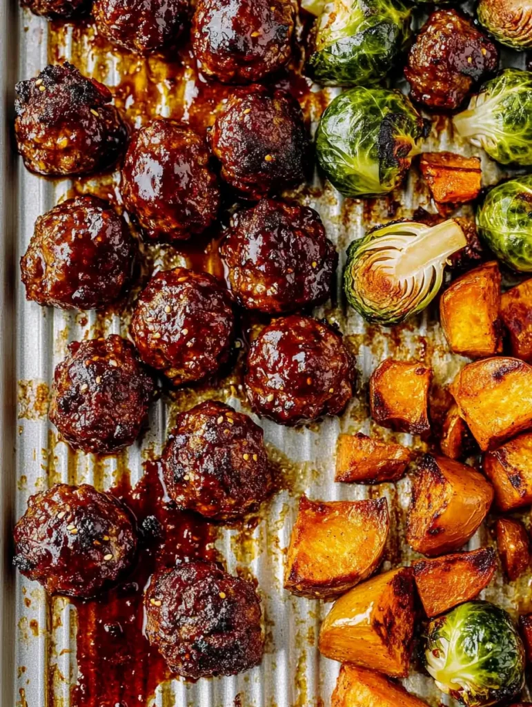 Korean BBQ Meatballs and Vegetables 4 Close view of a rimmed pan filled with caramelized Korean BBQ Meatballs and Vegetables, including halved brussels sprouts and roasted sweet potatoes, coated in Korean Bbq Sauce for that Bbq Meatballs sheen perfect for a Weeknight Dinner.