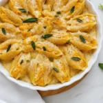 Pumpkin & Gouda Stuffed Shells With Brown Butter & Sage Alfredo Sauce 5 A round white baking dish of golden Stuffed Shells shows Pumpkin & Gouda Stuffed Shells With Brown Butter & Sage Alfredo Sauce, with Jumbo Pasta Shells nestled in creamy Alfredo Sauce and sage leaves for cozy Fall Comfort Food and Pumpkin Pasta vibes.