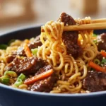 Slow Cooker Beef Ramen Noodles 5 Bowl of Slow Cooker Beef Ramen Noodles with tender beef strips, carrots, scallions, sesame seeds, and chopsticks ready to serve
