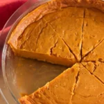 Slice of crustless pumpkin pie on a white plate with whipped cream and a fork, smooth custard texture, easy healthy fall dessert