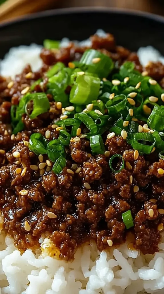 Close up of Korean Ground Beef Bowl, glossy sesame soy beef on fluffy white rice with chopped scallions, quick family meal prep idea