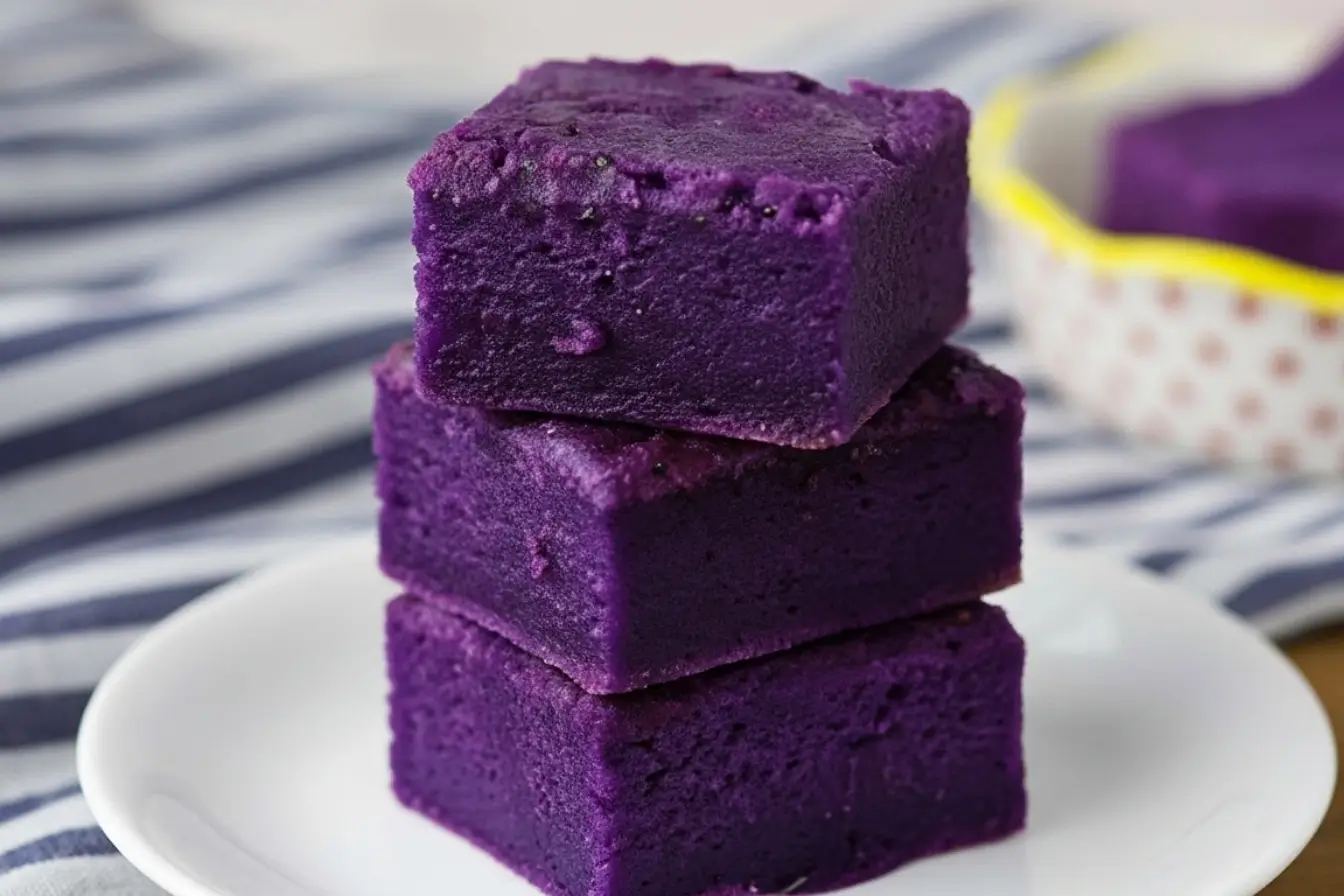 Ube Mochi Recipe - How to Bake Chewy Purple Yam Mochi Bars at Home 3 Ube Mochi Recipe, three vibrant purple mochi bars stacked on a white plate, chewy Butter Mochi texture, Filipino Food Dessert idea for easy baked ube squares
