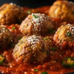 Vegetarian cauliflower meatballs simmered in tomato sauce, sprinkled with parmesan and parsley, with jalapeño slices and a fork in the pan