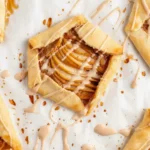 Easy Pear Galettes on parchment, rustic puff pastry squares filled with thinly sliced pears and cinnamon, finished with a light glaze drizzle, perfect quick pear dessert