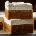 Frosted Gingerbread Brownies stacked on a board, chewy spiced bars with creamy frosting, perfect for holiday baking and cookie exchange