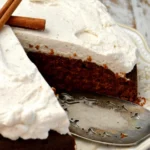 Gingerbread Molasses Cake topped with creamy cinnamon molasses frosting on a patterned plate, served with coffee and cinnamon sticks