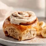 Banana bread cinnamon rolls with creamy cheese frosting on a plate
