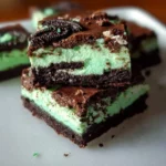 Triple Layer Mint Oreo Brownies topped with mint cream and Oreo crumbs.