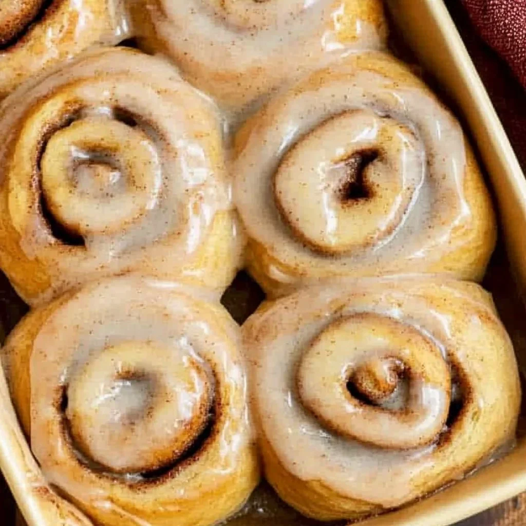 Freshly baked apple butter cinnamon rolls with icing on top.